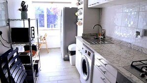 A compact kitchen with a washing machine, a sink, and a stove. - Entire House in Canterbury Centre - Free Parking - WiFi (Canterbury)
