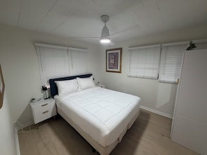 A bedroom with a bed, bedside tables, a nightstand, a ceiling fan, and a window with blinds. - Walk to Beach 2- Patios Updated Lux Retreat NEW Heated Pool Sleeps 10 Small Dogs (Naples)