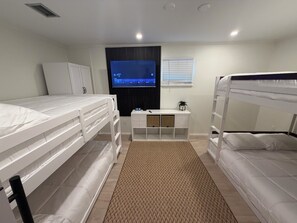 A bedroom with bunk beds, a TV, a desk, and a wardrobe. - Walk to Beach 2- Patios Updated Lux Retreat NEW Heated Pool Sleeps 10 Small Dogs (Naples)