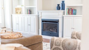 A living room with a fireplace, white cabinets, and a patterned armchair.
