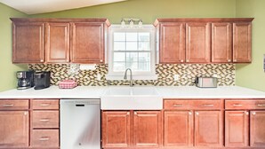 A kitchen with wooden cabinets, a white countertop, a dishwasher, a coffee maker, and a toaster.