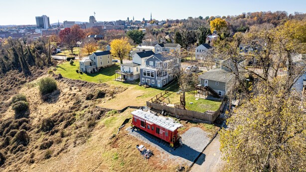 A residential area with houses, a train track, and a distant city skyline.