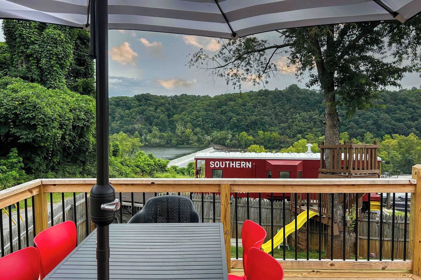 Een terras met uitzicht op een rivier en bos, een rood gebouw met de tekst 'SOUTHERN' en een gele glijbaan.
