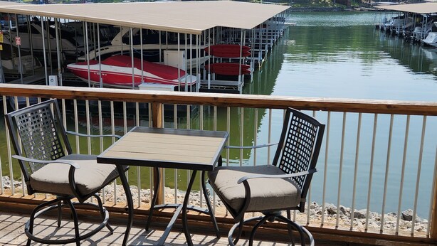 A covered deck with a table and chairs, overlooking a marina with boats docked. - 2 bed King Master/2 bath condo with lake access and large 16 x 40 boat slip (Osage Beach)