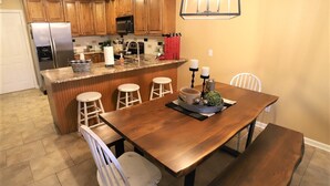 A kitchen with wooden cabinets, a stainless steel refrigerator, a built-in island with stools, and a dining table with chairs. - 2 bed King Master/2 bath condo with lake access and large 16 x 40 boat slip (Osage Beach)