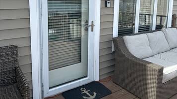 A house with a 'BAYVIEW' sign, a sliding glass door, a wicker sofa, and a doormat with an anchor symbol.