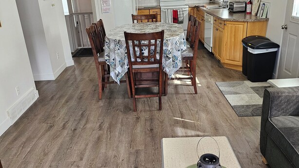Een ruime keuken met houten kastjes, een eethoek met een tafel en stoelen, en een plafondventilator.