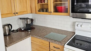 Een keuken met houten kastjes, een rvs magnetron, een koffiezetapparaat en een waterkoker.