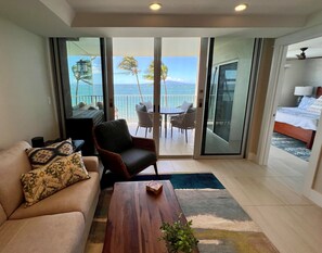 Enjoy ocean views and palm trees from the balcony, featuring a sofa, coffee table, and a small plant.