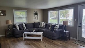 A living room with a sectional sofa, a white coffee table, and two lamps on side tables. - Beautiful Sunrises and Lakefront Views! (Fond du Lac)
