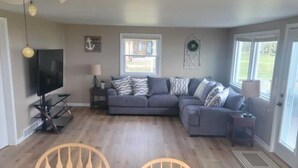 A dining area with a wooden table and chairs, a ceiling fan, and a television on a stand. - Beautiful Sunrises and Lakefront Views! (Fond du Lac)