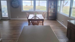 A spacious kitchen with a dining area, large windows, and a view of the outdoors. - Beautiful Sunrises and Lakefront Views! (Fond du Lac)