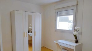 A room with a white wardrobe, a desk with a chair, and a window with a view of buildings. - Comfortable room near Paris and transport (Achères)