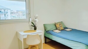 A small, neatly arranged bedroom with a single bed, a desk, and a chair. - Comfortable room near Paris and transport (Achères)