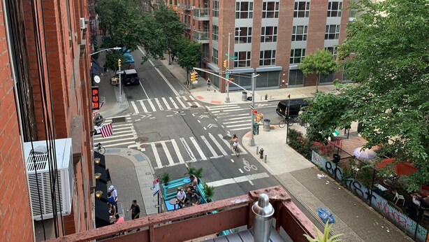 A street view with a crosswalk, buildings, and a pedestrian. - True 1Bdrm (New York)