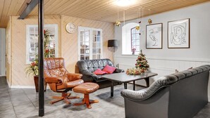 A cozy living room with a leather sofa, a matching armchair, and a small coffee table. There is a Christmas tree on a table, and artwork on the wall. - Awesome apartment in Esbjerg V (Esbjerg V)