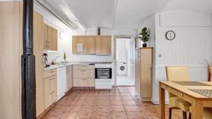 A compact kitchen with wooden cabinets, a stove, oven, and a washing machine. - Awesome apartment in Esbjerg V (Esbjerg V)