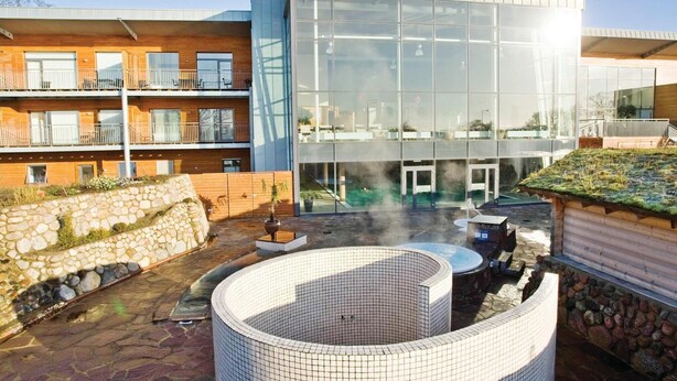 A modern building with large glass windows, a stone wall, and a circular hot tub area. - 4 bedroom awesome home in Gråsten (Gråsten)