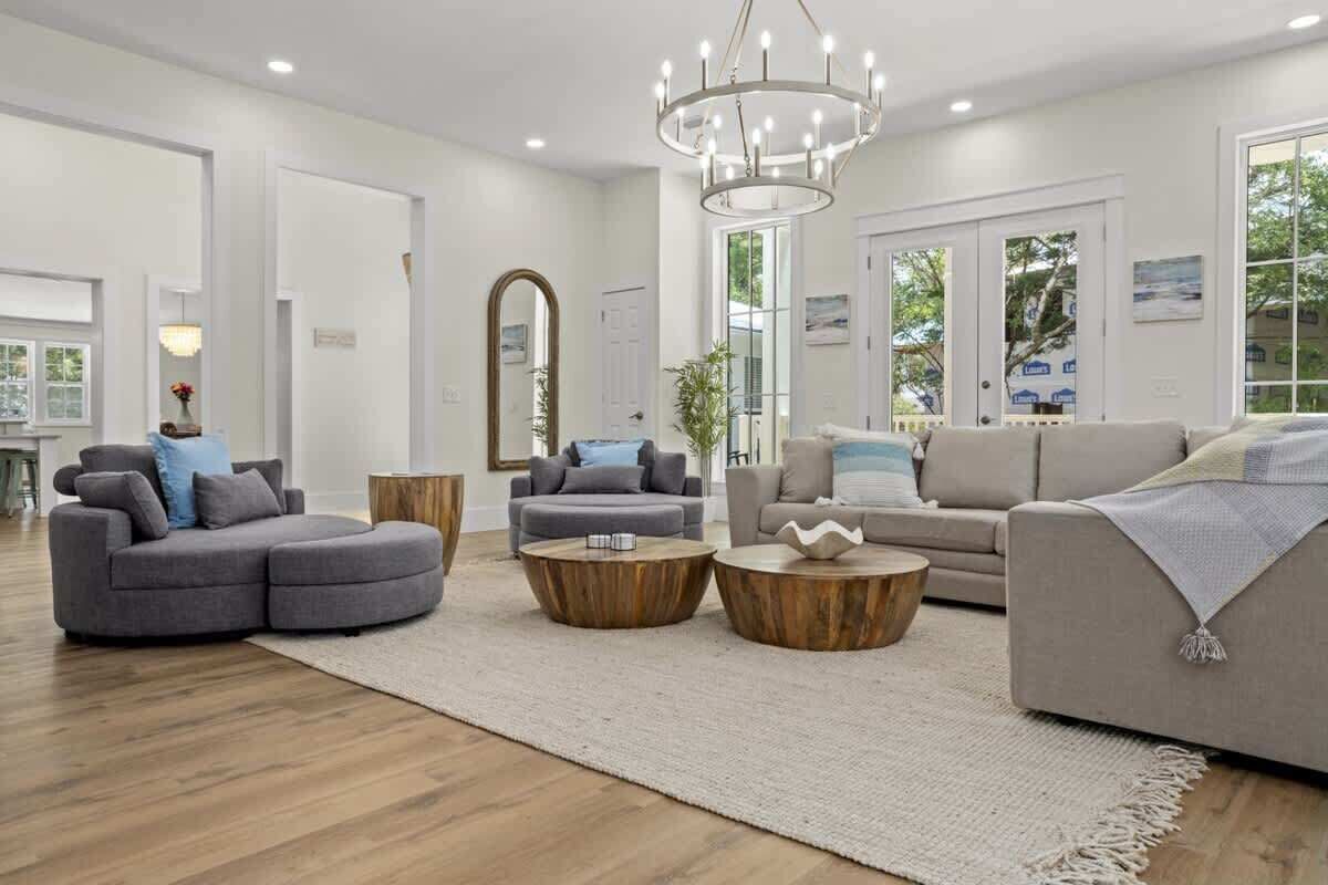 A modern living room with a sectional sofa, two round wooden coffee tables, and a chandelier.