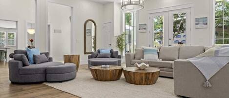 A modern living room with a sectional sofa, two round wooden coffee tables, and a chandelier.