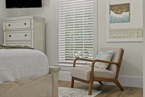 A bedroom with a bed, a wooden dresser, a chair, and a window with blinds. - Luxury 8BR Home w/ Pickleball, Pool & Spa (Santa Rosa Beach)