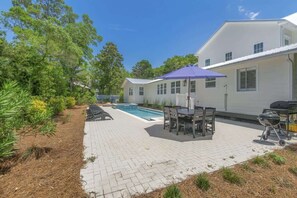 A patio with a pool, outdoor furniture, and a barbecue grill.