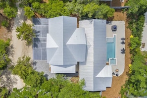 Una casa moderna con una terraza amplia, piscina y zona de estar cubierta al aire libre.