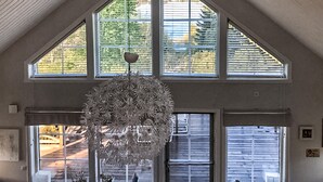Een ruime kamer met grote ramen, een hanglamp en uitzicht op de omgeving.