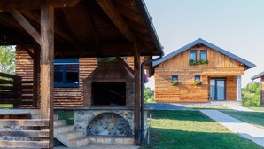 Eine rustikale Holzhütte mit Kamin aus Stein, Holzfassade und einer Veranda.