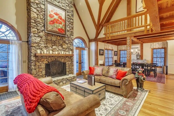 A spacious living room with a stone fireplace, wooden beams, and a cozy seating area. - Luxe Private Getaway in the Heart of Wintergreen! (Roseland)