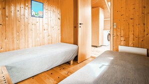 A wooden cabin with two single beds, a washing machine, and a framed picture on the wall. - 3 bedroom gorgeous home in Væggerløse (Væggerløse)