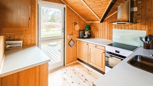 A wooden cabin kitchen with a sliding glass door, a stove, and a sink. - 3 bedroom gorgeous home in Væggerløse (Væggerløse)