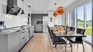 Una cocina moderna con comedor, ventanas amplias y vistas al exterior.