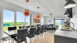 Una cocina moderna con comedor, ventanas amplias y vistas al campo.