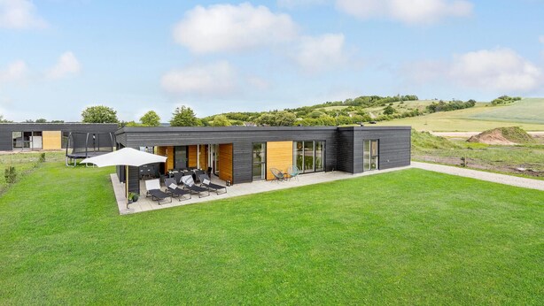 Una casa moderna con un patio que incluye mobiliario exterior y un trampolín.