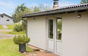 Guests can enjoy a cozy porch area with a door and window, a grassy lawn, and a pathway leading to this charming single-story building.