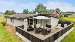 A modern outdoor patio area with a covered seating area, a barbecue grill, and a view of the surrounding neighborhood.