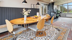 A dining area with a wooden table, four chairs, a vase with flowers, and a fruit bowl.