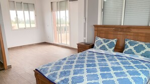 A bedroom with a wooden bed, a nightstand, and a window with blinds. - American Farm Villa El Jadida, Sidi Rahal, Azemour  (Casablanca-Settat)