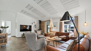 Un salon moderne doté d’un téléviseur à écran plat, d’une cheminée, d’un canapé, d’une table basse et d’une grande fenêtre.