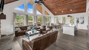 A spacious living area with a high ceiling, large windows, and a central seating area with sofas and a coffee table. - Copper Rock Ridge |Hot Tub |Pool Table| Near Zion (Orderville)