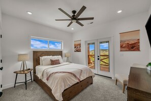 A bedroom with a bed, a ceiling fan, a window, and a door leading to an outdoor area. - Copper Rock Ridge |Hot Tub |Pool Table| Near Zion (Orderville)