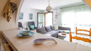 En moderne stue med en grå sofa, et spisebord med en skål og en dekorativ tallerken, samt en hængende lampe.