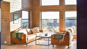 Ein gemütliches Blockhaus-Interieur mit Holzausstattung, einer Couch, einem Couchtisch und Blick auf den Wald.
