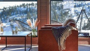 Ein modernes Wohnzimmer mit einem großen Fenster mit Blick auf eine verschneite Berglandschaft.