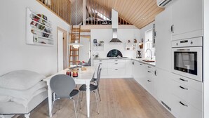A modern kitchen with white cabinetry, a wooden ceiling, and a built-in oven. - 2 bedroom beautiful home in Kerteminde (Kerteminde)