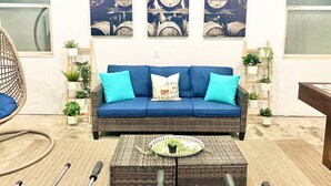 Un salon avec un canapé bleu, une table basse en osier et des jardinières fixées au mur.