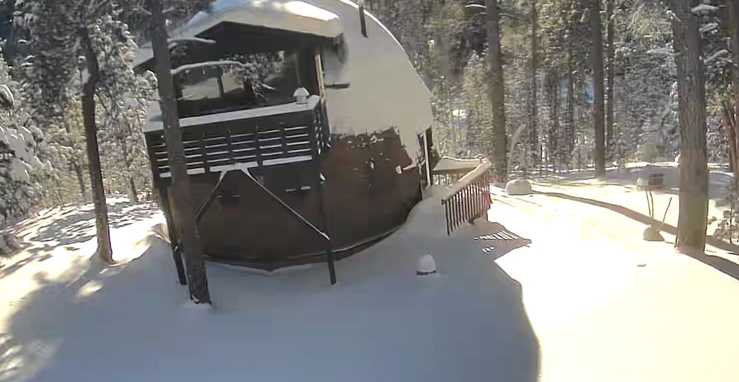 Una caravana cubierta de nieve con una parrilla frontal y un pequeño porche.