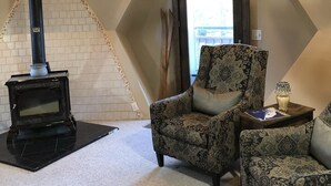 A cozy living room with a fireplace, patterned armchairs, and a wooden table.