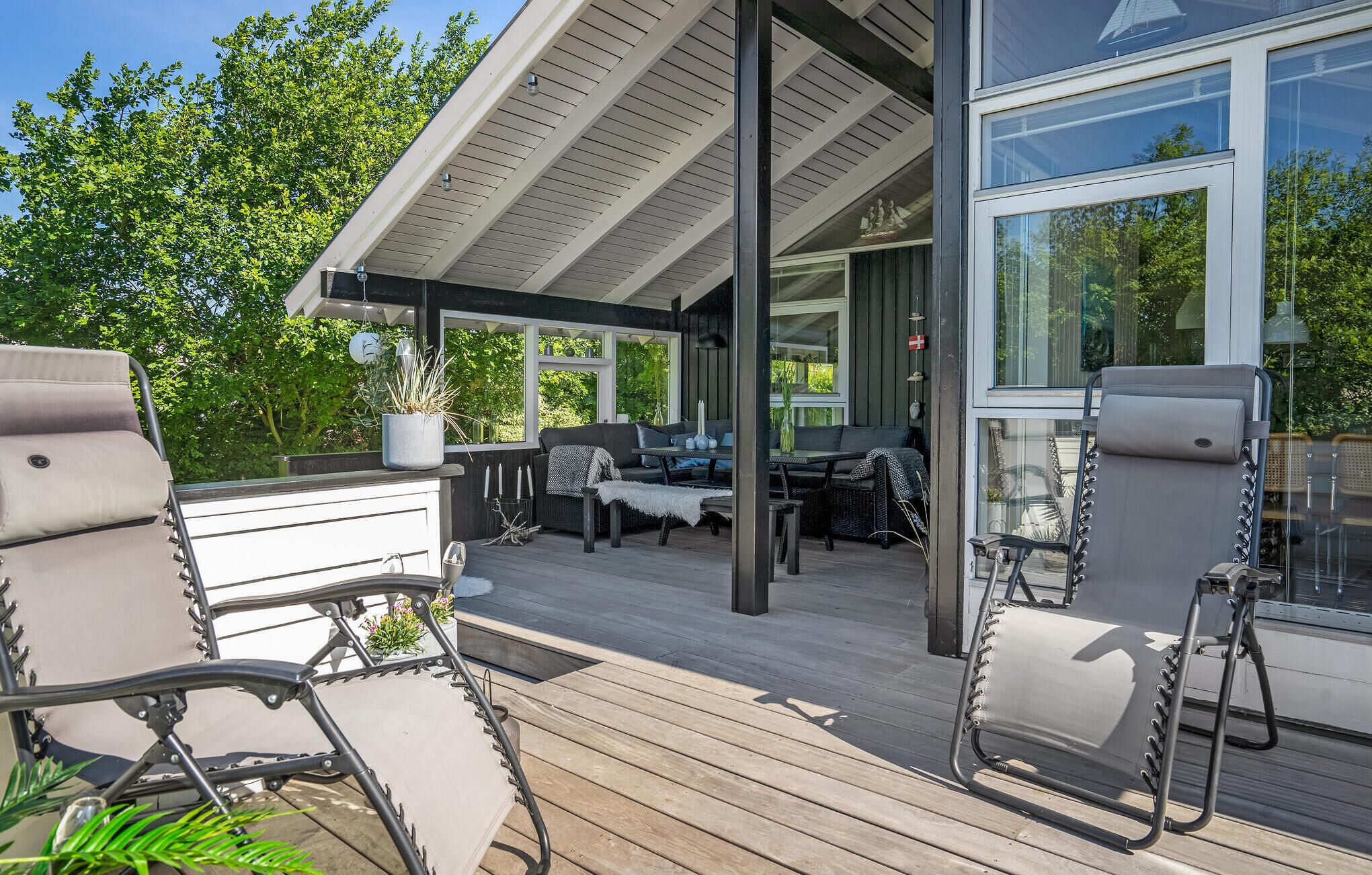 An outdoor deck with seating, a grill, and a potted plant.